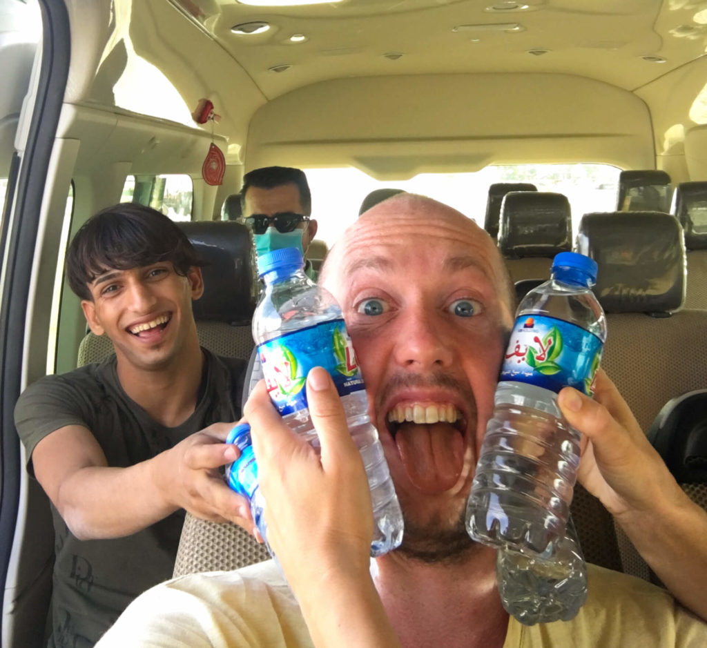 Me with water bottles being held to my face to cool me down and an Iraqi kid grinning from ear to ear behind me.