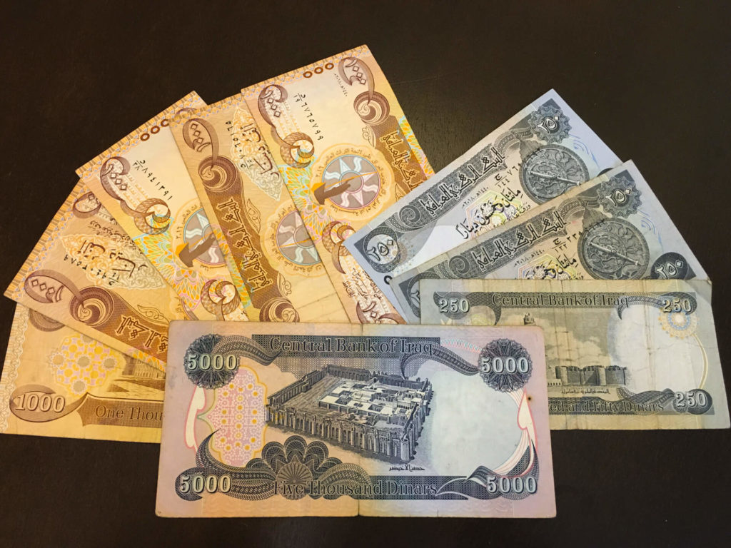 Several Iraqi dinar notes spread out on a table