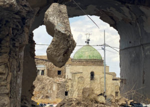 The green dome of the Umayyad Mosque seen through a hole in the wall of a building in the old town of Mosul.