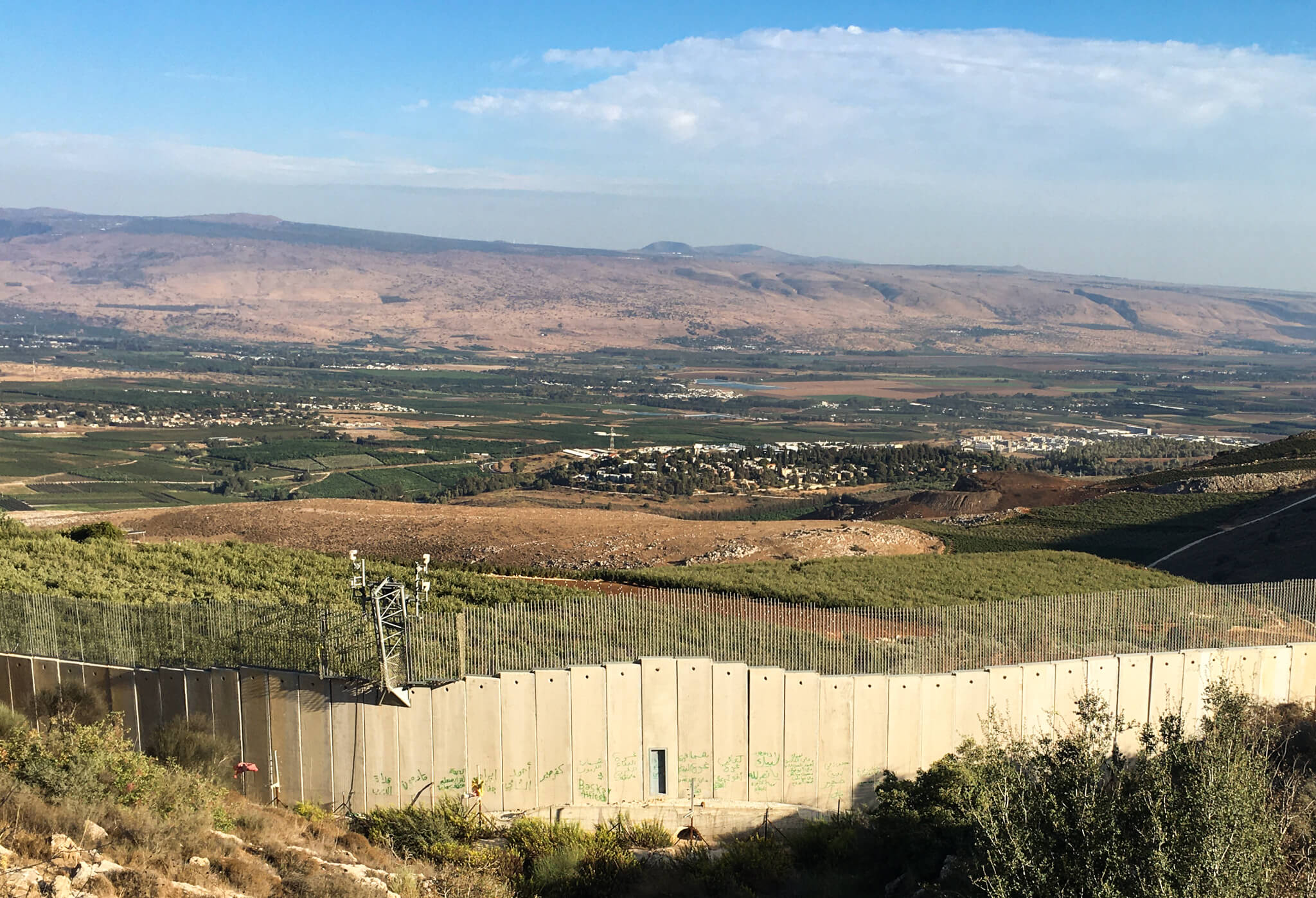 Concrete and wire border wall with security cameras on it