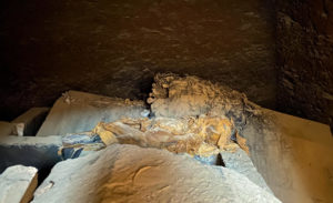 A small mummy inside an open tomb.