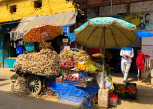 A colourful market stand with piles of fresh garlic.